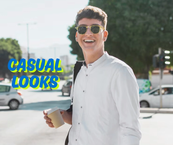 How to Style Linen Shirts for Men in 2025 2 A young man with short brown hair, wearing a white collared shirt, light-colored sunglasses, and carrying a black bag over his shoulder, smiles brightly while holding a disposable cup in his left hand. He is standing on a city street with cars and buildings in the blurred background. The words "CASUAL LOOKS" are superimposed in blue and yellow on the left side of the image.
