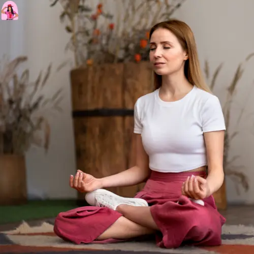 Shocking Secrets of Top Instagram Brands for Women's Summer Fashion 5 A woman with long hair meditates in a seated lotus position. She is wearing a white t-shirt and loose pink pants, with her eyes closed in a calm expression.