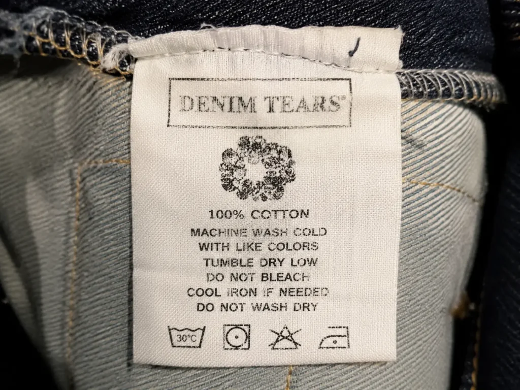 The Fake Denim Tears Trap: Unmasking Counterfeits and Protecting Your Style 3 Examining labels and hardware on fake Denim Tears apparel to identify counterfeits.